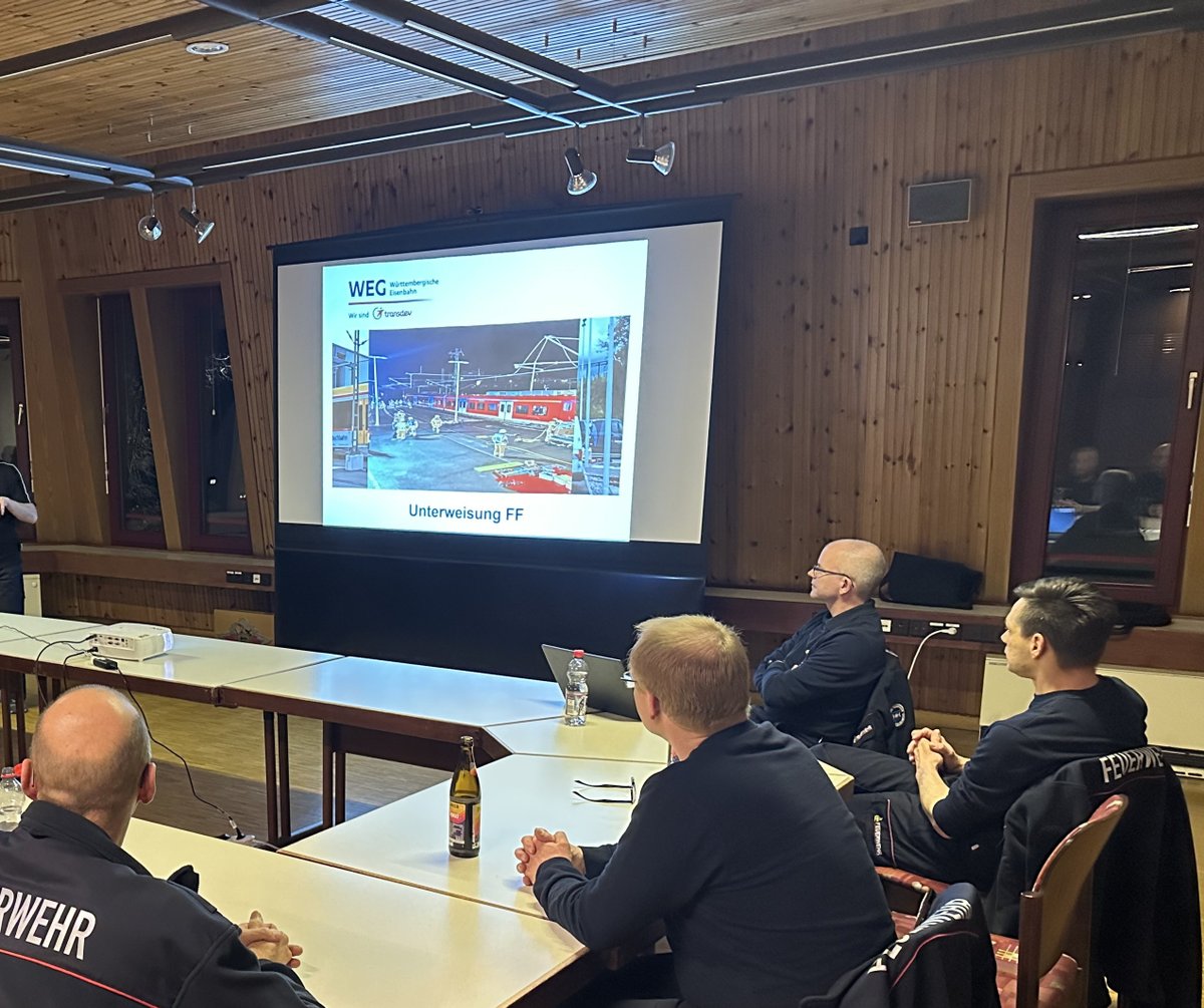 Ein Mitarbeiter der WEG steht in einem Vortragsraum vor den Feuerwehrleuten, im Hintergrund ist eine Präsentation zu sehen