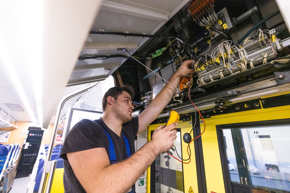 Auszubildender prüft Elektronik des Zuges.