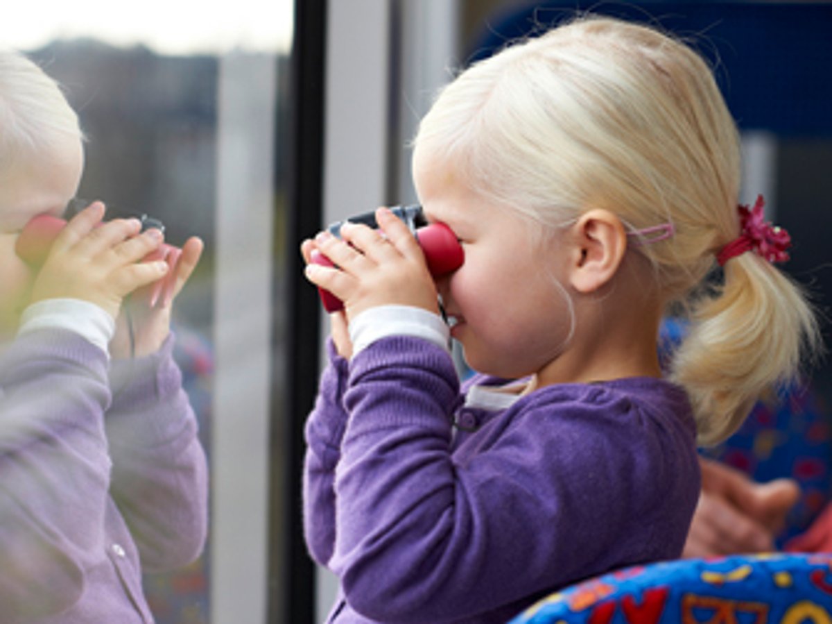 Kind schaut mit Fernglas aus Bus