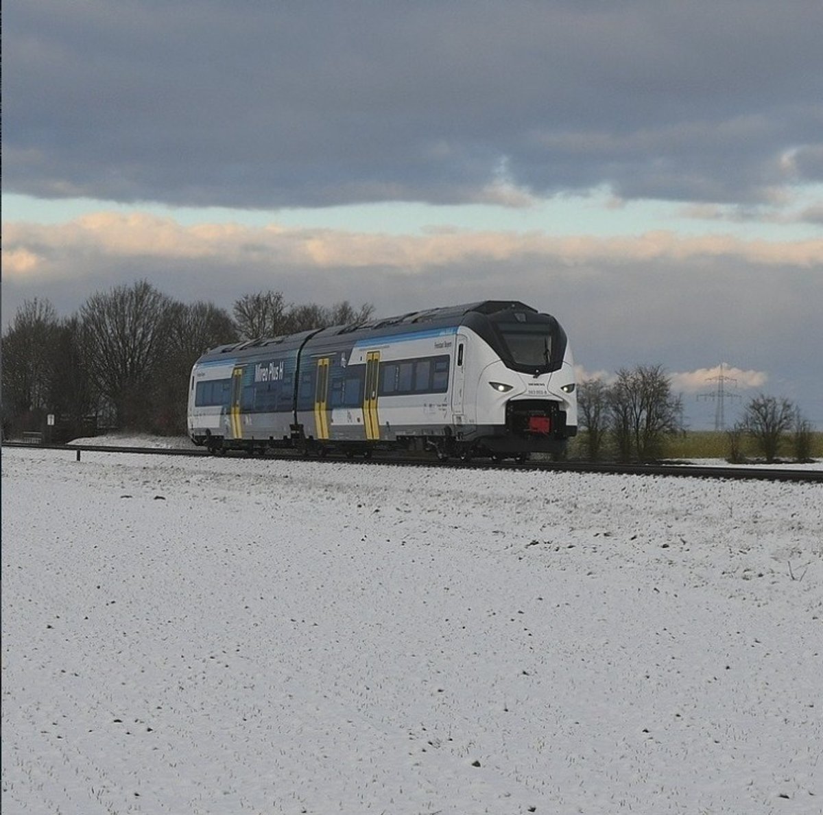 Der Wasserstoffzug Mireo Plus H fährt durch die verschneite Winterlandschaft bei Großaitingen und zeigt, wie umweltfreundliche Mobilität bei der BRB aussieht.