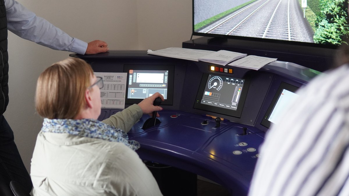 Frau von hinten bedient einen Zugsimulator.