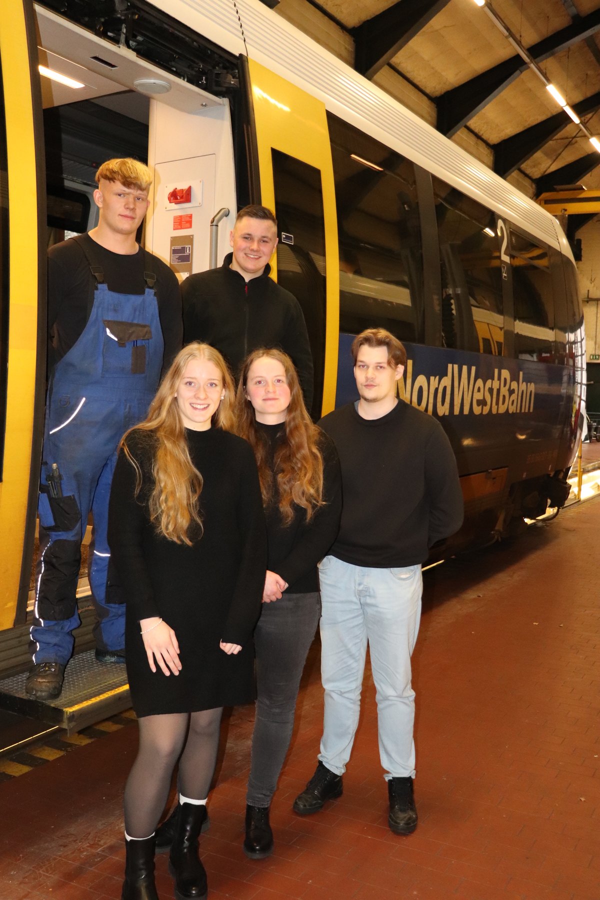 Fünf Menschen vor einem Zug. 
