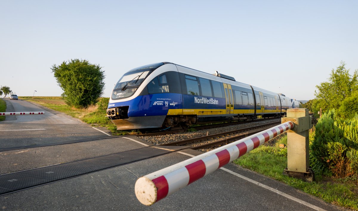 Ein Zug der NordWestBahn passiert einen geschlossenen Bahnübergang. 